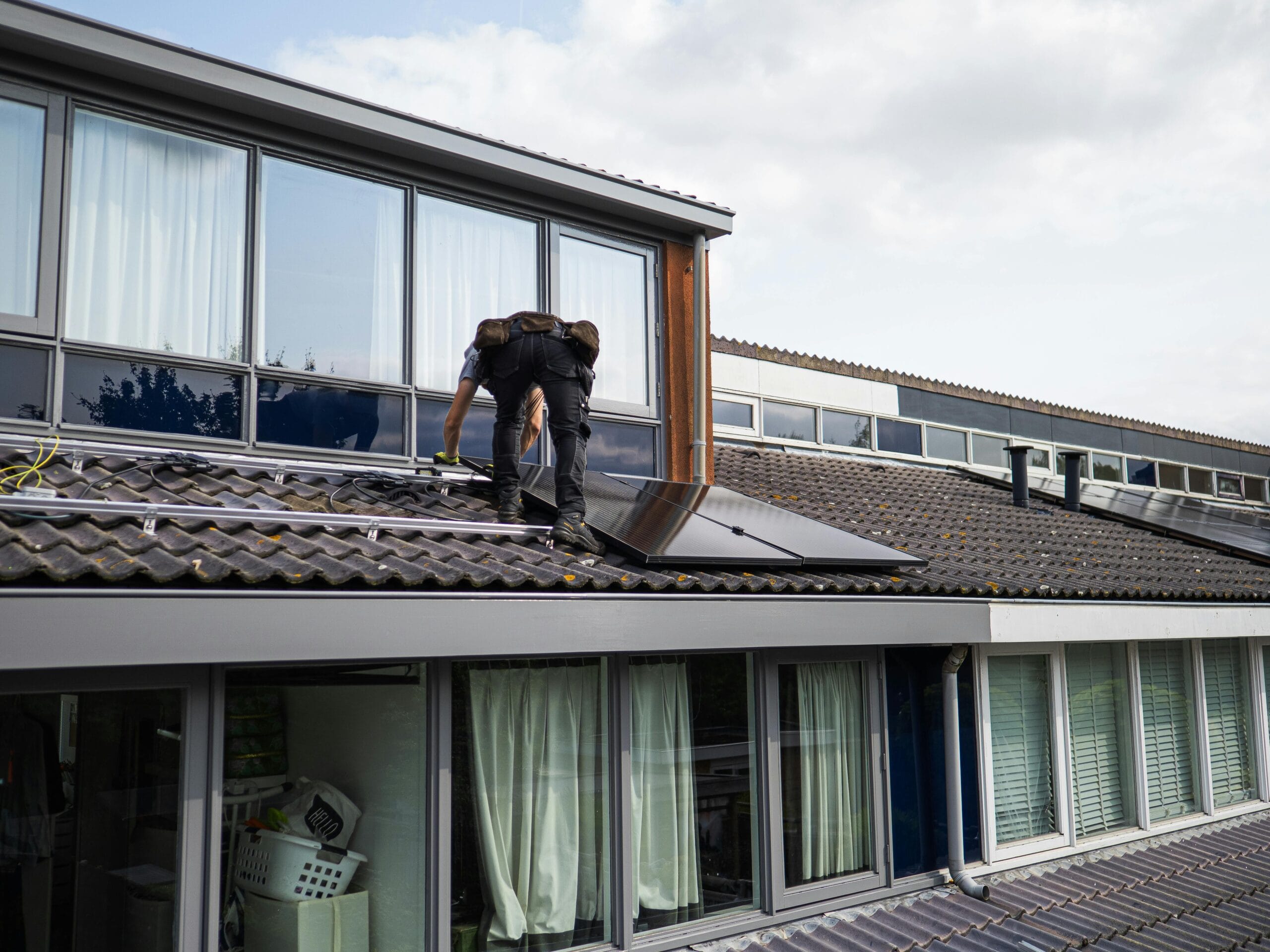 pexels-sdvmovies-29206488 A person installing solar panels on a rooftop.
